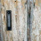 A vintage thermometer mounted on a rustic wooden wall. Perfect for themes of nostalgia and weather monitoring.